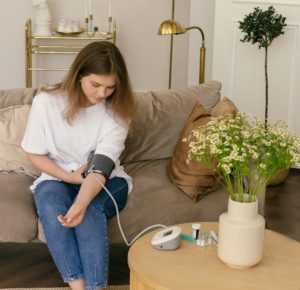 Woman taking her blood pressure with a device at home